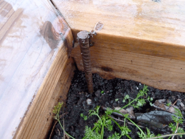 Rebar hammered into place inside the corner of the raised bed